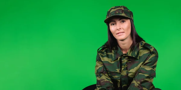 Banner de formato largo. Retrato de una linda mujer en uniforme militar mirando a la cámara sobre un fondo verde con espacio lateral en blanco. — Foto de Stock