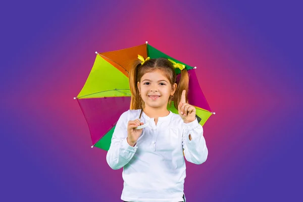 Fille préscolaire avec parapluie sur fond coloré avec index vers le haut. Concept d'émotion avec espace vide. — Photo