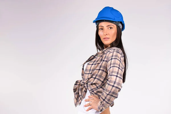 Retrato de una joven ingeniera caucásica de sombrero duro azul posando sobre fondo gris con espacio en blanco. — Foto de Stock