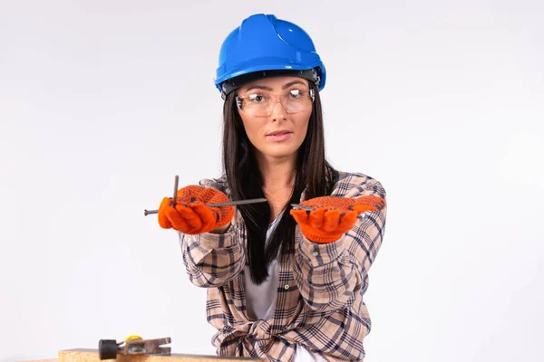 Söta kvinnor i hjälm och glasögon poserar med naglar i händerna på en vit bakgrund. — Stockfoto