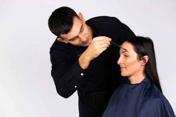 Male make-up artist does makeup for a business woman. Beauty, fashion and gender stereotypes isolated on white.