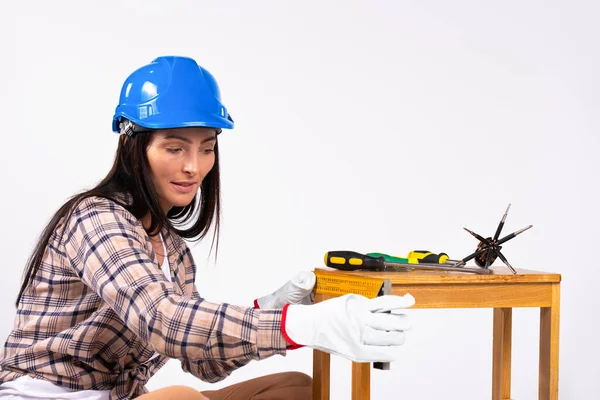 Kvinna i hård hatt och handskar arbetar i koncentration på en vit bakgrund. Begreppet könsstereotyper. — Stockfoto