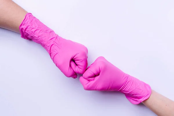 Γροθιές σε λευκό φόντο. Ροζ γάντια λάτεξ και μια νέα ιδέα καλωσορίσματος με πλευρικό χώρο. — Φωτογραφία Αρχείου