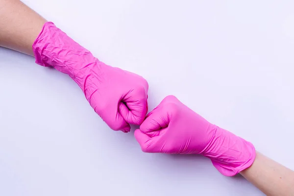 Puños sobre fondo blanco. Guantes de látex rosa y un nuevo concepto de bienvenida con espacio lateral. — Foto de Stock