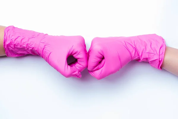 Hände in rosa Latex-Handschuhen grüßen Faust in Faust. Neues Konzept der Begrüßung während einer Pandemie und auf weißem Hintergrund. — Stockfoto