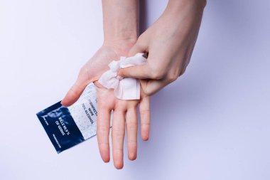 Eller alkolün üzerine antibakteriyel mendillerle avuç içi temizliyor. Beyaz arkaplan.