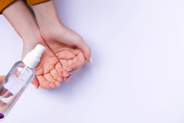 Προστασία των χεριών από βακτήρια. Γυναικεία χέρια και αντισηπτικό σπρέι σε λευκό φόντο. — Φωτογραφία Αρχείου