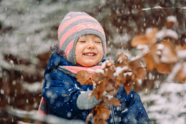 Snowy zimowy dzień i portret małej uśmiechniętej dziewczynki w płatkach śniegu. — Zdjęcie stockowe