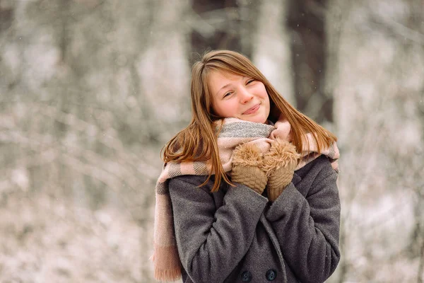 Portrait d'une fille blonde souriante dans une écharpe chaude et des gants dans la forêt d'hiver. — Photo