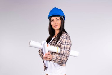 Mavi şapkalı ciddi bir kadın mimar. Gri arka planı ve boş bir yan alanı var. Cinsiyet klişeleri kavramı.