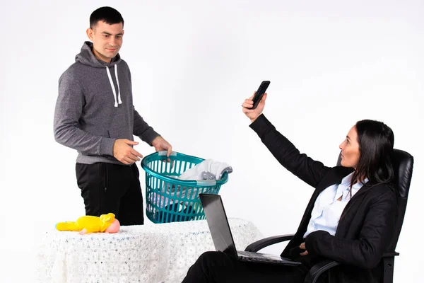 Um homem limpa a casa, e sua namorada, uma mulher de negócios, trabalha em um laptop e tira uma selfie. Fundo branco. — Fotografia de Stock