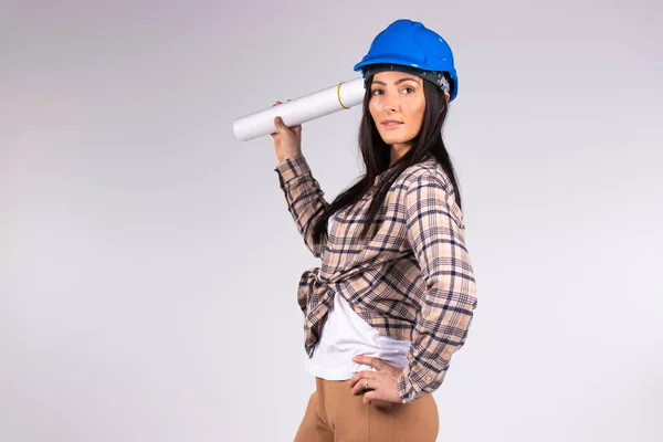 Jovem arquiteto menina em hardhat posando bonito em um fundo branco com espaço em branco lateral. — Fotografia de Stock