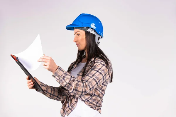 Uma engenheira examina documentos em um fundo branco com espaço lateral em branco. — Fotografia de Stock