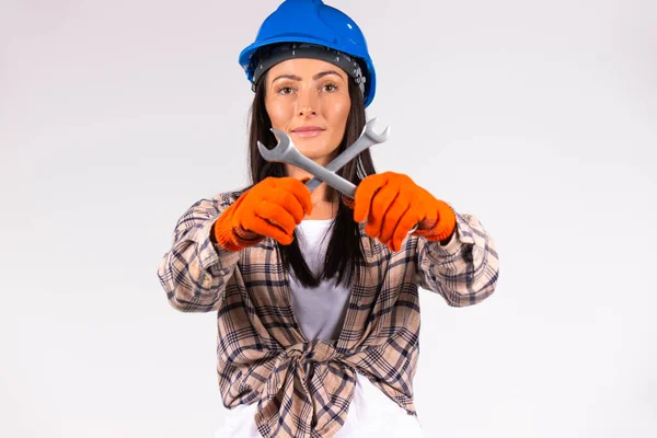 Young mechanic in a hard hat poses with tools on a white background and looks into the camera. Side white space. — Stock Photo, Image