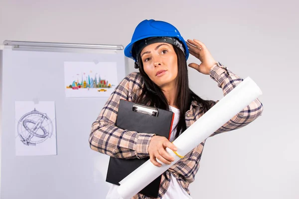 Ung kvinna i hård hatt med dokumentation och projekt talar i telefon på ett kontor bakgrund. — Stockfoto