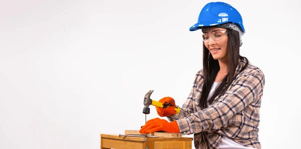 Banner. En kvinna byggare i hjälm, handskar och glasögon med en hammare på en vit bakgrund. — Stockfoto