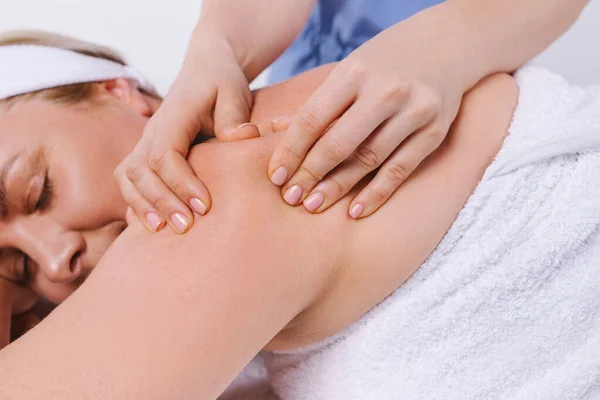 Foto ampliada onde as mãos do massagista massageiam as costas de uma mulher com uma toalha branca invertida. — Fotografia de Stock