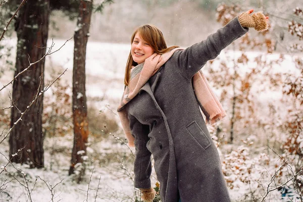 Joyeux jeune fille souriant et s'amusant à écarter ses bras sur les côtés dans la forêt enneigée d'hiver. — Photo