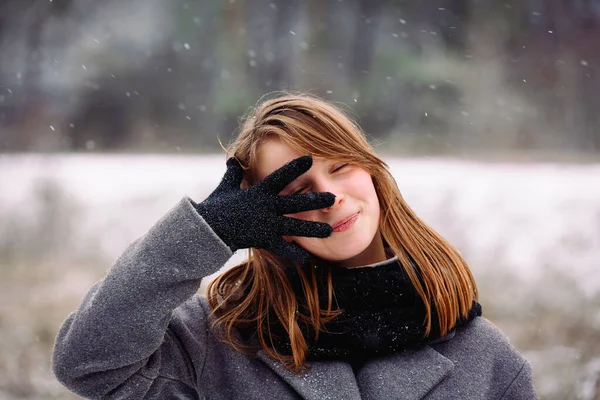 Jolie petite fille souriante et posant couvrant une partie de son visage avec sa main. Des paysages. Fond d'hiver. — Photo