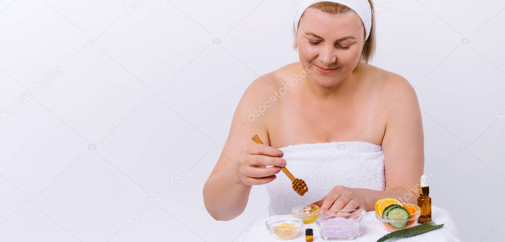 Banner- long format. A elderly woman prepares at home a natural scrub, face and body mask from honey. Healthy skin care. Elixir of youth on white background and side space.