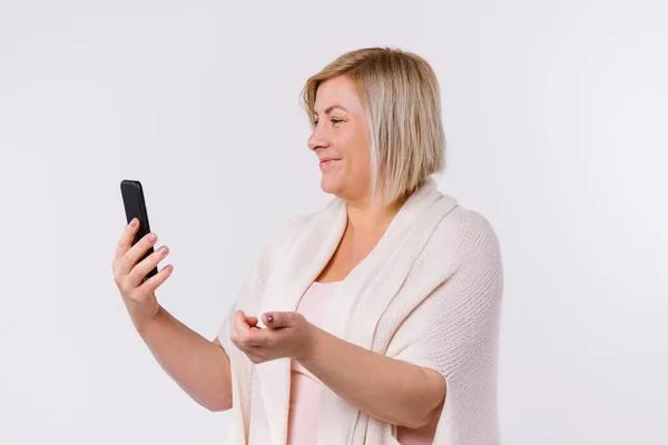 Vit kvinna ler och kommunicerar via videokommunikation. Vit bakgrund. Profilfoto. — Stockfoto