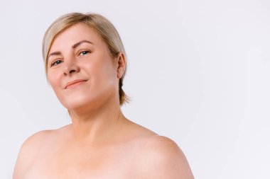 Temiz tenli, beyaz arka plandaki kameraya bakan tatlı, son sınıf öğrencisi kadın..