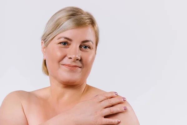 Beyaz arka planda yaşlı bir kadının büyütülmüş portresi. Gülümsüyor ve kameraya bakıyor..