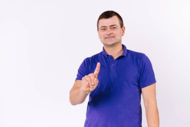 Kafkasyalı adam işaret parmağını havaya kaldırdı. Beyaz arka planda, boş bir yan alanı olan sıradan tişörtlü, işitme zorluğu çeken bir adam..