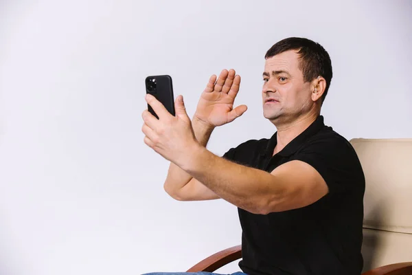 Non-verbal greeting. Hard of hearing senior man communicates via video on modern smartphone. White background and side blank space. — Stock Photo, Image