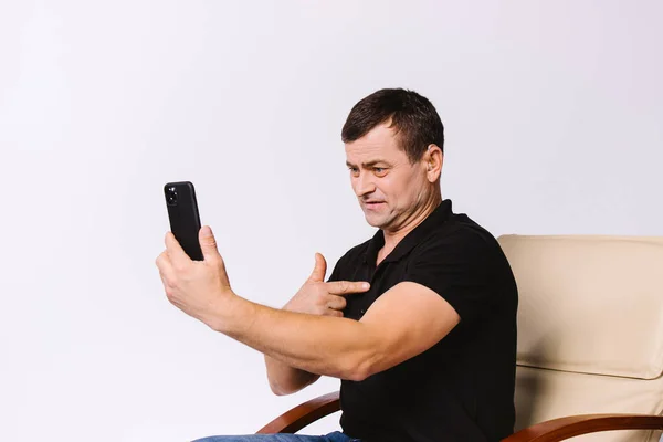 Senior hearing impaired man work in office, emotionally communicates with gestures via video call on smartphone on white background. — Stockfoto
