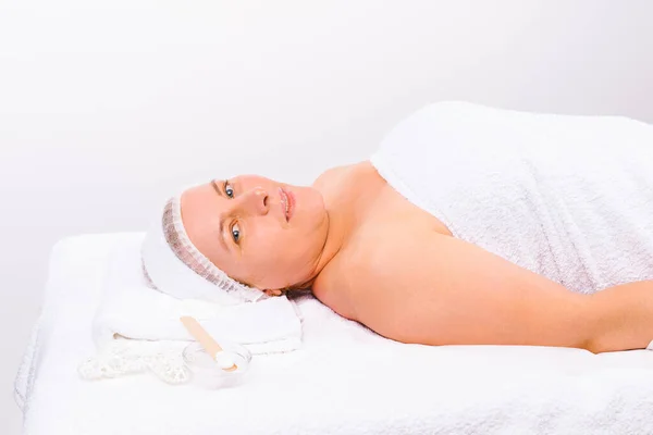 Enlarged photo. The beautician applies a moisturizing mask to the face of an older woman with a brush. — Stock Photo, Image