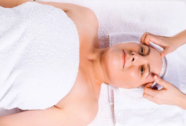Foto dall'alto. Le mani di massaggiatore che fa il massaggio di testa a donna più anziana in salone su tessuto bianco. — Foto Stock