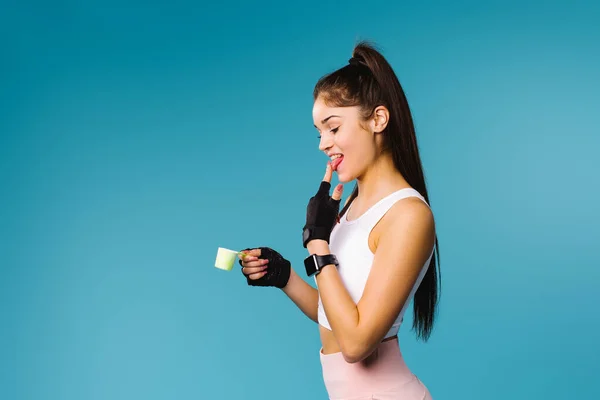 Kokteyl niyetine protein sütlü esmer kız. Vücut geliştirme ve bağımlılık kavramı. Boşluklu mavi arkaplan.