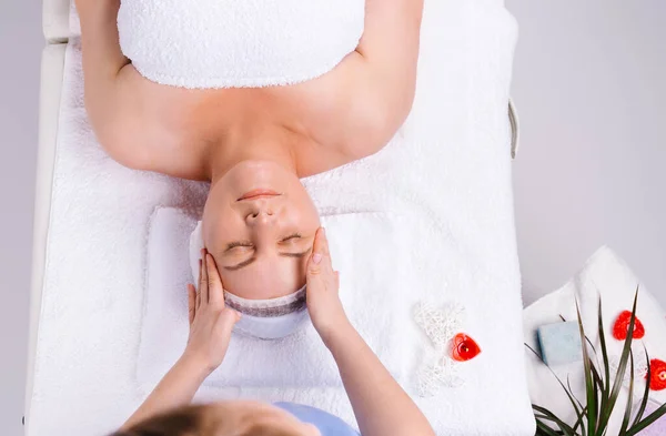 Foto van boven. handen van vrouwelijke masseur geven hoofd massage naar senior vrouw in salon met geurende kaarsen en witte achtergrond. — Stockfoto