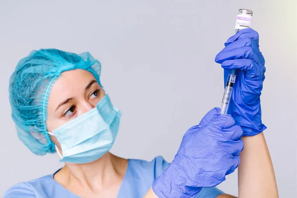 Retrato de una joven doctora con una jeringa y ampolla preparando la vacuna para covid 19. Vacunación médica sobre fondo gris. — Foto de Stock