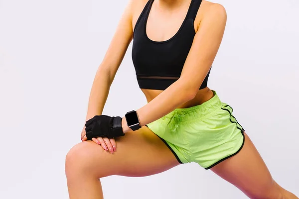Atletik fiziği ve spor saati olan bir kızın kesilmiş fotoğrafı. Beyaz arkaplandaki kasları esnetme egzersizleri. — Stok fotoğraf