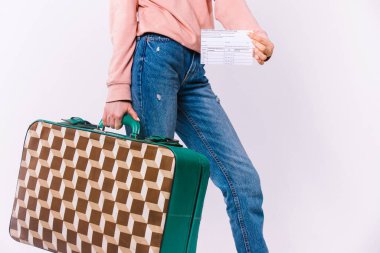 Beyaz arka planda bir bavul ve aşı sertifikası olan bir kadın eli var. Bir salgın sırasında seyahat kavramı.