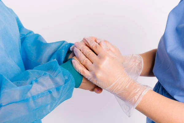 Una foto ampliada de las manos donde un trabajador médico con guantes sostiene las manos de los pacientes como un signo de apoyo. Devolución, voluntariado y asistencia social — Foto de Stock