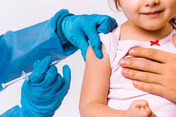 Fotografía recortada. Los médicos con guantes de látex ponen un pinchazo en el antebrazo de una niña. Vacunación contra el covidio 19. — Foto de Stock