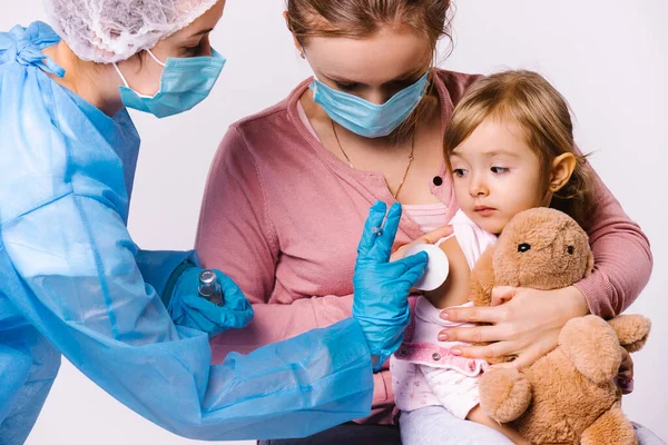 Mamá sostiene al niño en sus brazos y se calma después de la vacunación. El médico coloca una almohadilla de algodón en el lugar de la inyección. Fondo blanco. — Foto de Stock