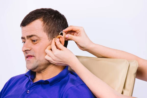 Portrét staršího muže s naslouchátkem na bílém pozadí. Nové technologie Pomoc při nedoslýchavosti. — Stock fotografie