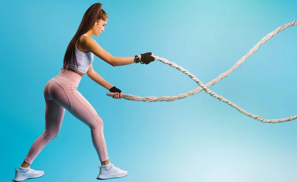 stock image A pumped-up girl throws the channel to the side on a blue background. Sport and healthy lifestyle concept.