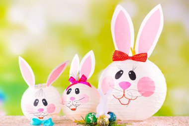 Yeşil arka planda el yapımı Paskalya tavşanları ailesi. Kağıt işçiliği dekorasyonuyla bayram hazırlığı. Anne tavşan ve çocukları. 