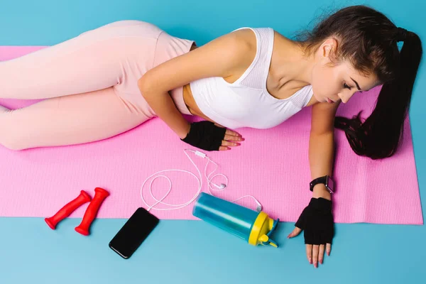 Fiatal lány fitness oktató egy rózsaszín szőnyegen a gyakorlatok közötti szünetben. — Stock Fotó