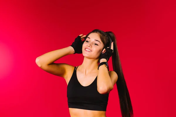 Портрет танцюючої дівчини у великих навушниках, дивиться в сторону і посміхається на червоному тлі з порожнім рекламним простором . — стокове фото