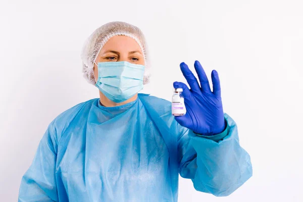 Läkare i medicinsk skyddsutrustning och latex engångshandskar håller i en ampull med vaccin och visar den för kameran. Vit bakgrund. Fighting covid 19. — Stockfoto