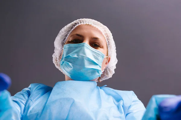 Медсестра в медицинском костюме и маске делает селфи на сером фоне. — стоковое фото