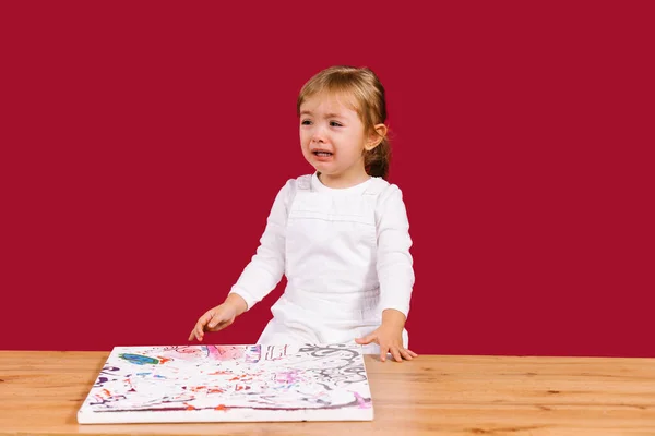 Liten flicka gråter sitter vid träbordet med duk bild set. Tålmodiga småbarn flicka väntar sin mamma komma att skapa målning av siffror — Stockfoto