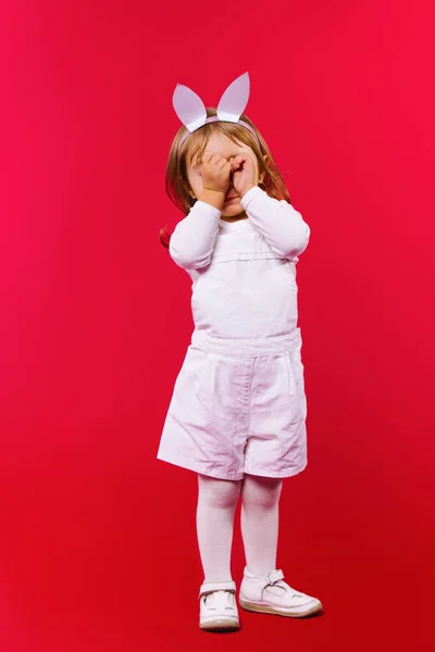 Маленькая милая малышка в милых ушах пасхального кролика и белом костюме, покрывающем лицо руками во время плача. Концепция депрессии. — стоковое фото