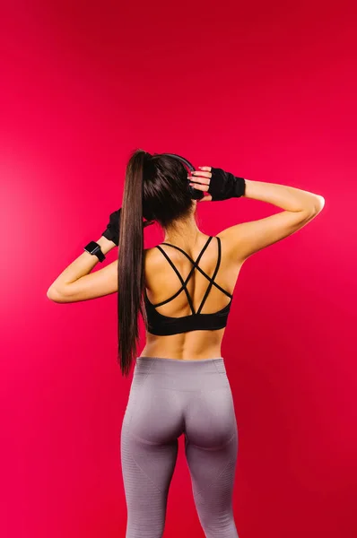 Een foto van de achterkant van een dansende brunette meisje met een atletische lichaamsbouw en gespierde billen op een rode achtergrond. — Stockfoto